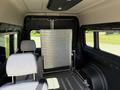 Interior of a 2021 RAM Promaster showing a grey bench seat and a metal partition behind it with a textured surface