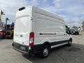A 2023 Ford Transit in white with a high roof and sliding side door parked with visible rear doors and wheels