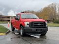 A red 2015 Ford F-150 truck parked with a black grille and chrome accents
