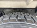 Close-up of a treaded tire on a 2010 Freightliner M2 106 showing distinct grooves and surface texture