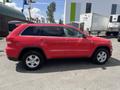 2015 Jeep Grand Cherokee in bright red with five-spoke wheels showing a side view