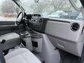 Interior view of a 2013 Ford E-350 showing front seats dashboard and control panel with gray upholstery and storage compartments