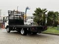A 2015 Hino 195 flatbed truck with a black paint finish and a mesh safety barrier at the rear