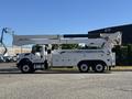 A 2013 International 7500 truck with a utility bucket attached to an extended arm positioned on the driver's side