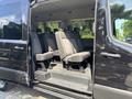 A 2025 Ford Transit T-350 with a side door open revealing multiple rows of gray seating arranged for passenger transport