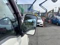 A white 2010 Daihatsu Hijet van with a side mirror reflecting surroundings