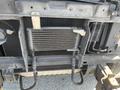 A 2012 Ford Econoline's undercarriage showing metal components and a cooling system with hoses and heat exchanger visible