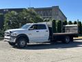 A white 2014 RAM 5500 flatbed truck with a wooden bed parked on a driveway