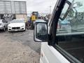 A 2010 Suzuki Carry van with a white exterior parked with raindrops on its side mirror