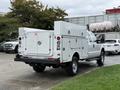 A white 2015 Ford F-350 SD truck with a service body featuring compartments on both sides and a closed rear door