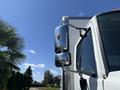 A close-up of the side mirror of a 2020 Hino 338 showcasing its chrome finish and orange light indicator