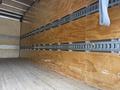 Interior view of a 2018 Hino 195 truck with wooden walls and metal cargo tie rails along the sides