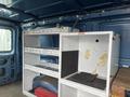 Interior of a 2006 Ford Econoline with white shelving units for storage and a wooden surface in the foreground