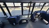 Interior view of a 2021 Ford Transit showing two blue driver's seats and control mechanisms on the floor between them