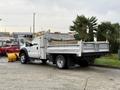 A 2013 Ford F-450 SD flatbed truck with a light gray body and metal bed parked in a lot