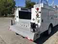 A white 2011 Ford F-550 truck with a flatbed and tool compartments on the rear featuring trailer lights and additional safety indicators