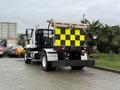 A 2016 Freightliner 108SD truck with a rectangular yellow and black checkered rear panel parked on a street