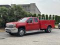 A red 2015 Chevrolet Silverado 3500HD with a flatbed and tool storage compartments on the sides