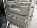 Interior door panel of a 2023 GMC Savana featuring a simple design with a handle and multiple storage compartments