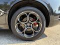 Close-up of a 2020 Alfa Romeo Stelvio's wheel featuring a sleek black and silver alloy design with prominent brake calipers in red