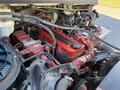 Close-up view of the engine compartment of a 2011 Freightliner M2 106 showing a red engine cover and various mechanical components with wiring and hoses