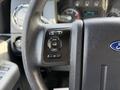 A close-up view of the steering wheel controls of a 2015 Ford F-550 featuring buttons for info setup reset and set