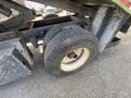 Close-up of a worn tire mounted on a truck's axle with visible tread patterns and rust on the rim