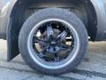A close-up view of a black wheel from a 2017 RAM 1500 featuring multi-spoke design and all-terrain tire tread