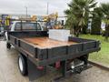 A rear view of a 2008 Ford F-350 with a flatbed featuring a wooden floor and a metal toolbox mounted in the center