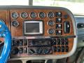 The dashboard of a 2009 Peterbilt Highway featuring various gauges knobs and a digital display along with a multimedia system