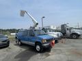 A blue 2005 Ford Econoline van with a white bucket lift attached on the roof parked in a vehicle lot