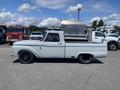 A light blue 1962 Ford truck with a short bed and black alloy wheels parked in a lot