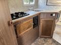 An interior view of a 2018 Westland Travelaire featuring a kitchen area with a sink a gas stove and wooden cabinets