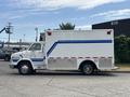 A 1994 GMC Vandura 3500 vehicle with a white exterior featuring blue stripes and red lights on the top and the side
