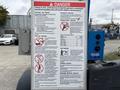 A safety warning sign on a Genie TZ-34/20 aerial lift listing various hazards and precautions related to its operation
