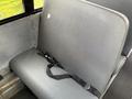 A gray bus seat with a safety strap featured in a Freightliner B2 model