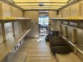 Interior of a 2012 Ford E-450 with metal shelving on the sides and two tires stacked on the floor