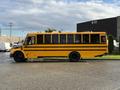 A yellow 2022 Freightliner B2 school bus with black stripes parked sideways