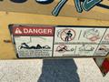 A visible safety warning sticker on a yellow Vermeer Corporation BC1200XL machine displaying danger symbols and instructions regarding limb safety when operating the equipment