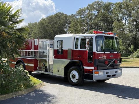 A red and white 1994 Volvo FE 42 fire truck with a ladder and equipment compartments on the side