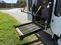 A 2013 Ford Econoline with a wheelchair lift extended at the rear of the vehicle