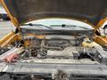 The image shows the open hood of a 2014 Ford F-150 revealing the engine compartment with various components including the battery and hoses.