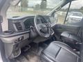 Interior view of a 2024 Ford Transit with black leather seats and a modern dashboard featuring a steering wheel and control panel