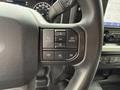 Close-up of the steering wheel controls of a 2021 Ford F-150 featuring buttons for navigation phone settings and menu options