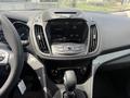 The interior of a 2015 Ford Escape showing the dashboard with a touchscreen display and control buttons situated below it
