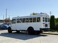 A white 2013 International CE300 school bus with large windows and black wheels parked with the rear view facing the camera
