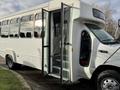 A white 2002 Ford Econoline bus with an open door and steps leading inside