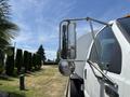 A 2015 Ford F-750 truck with a large side mirror reflecting the landscape and chrome detailing on the exterior