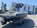 A 2013 Larson 238 boat on a trailer with a sleek black hull and white accents featuring a raised rear deck and multiple light fixtures on the transom