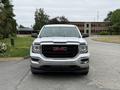 A 2016 GMC Sierra 1500 truck facing forward with a chrome grille featuring the red GMC logo and a silver body